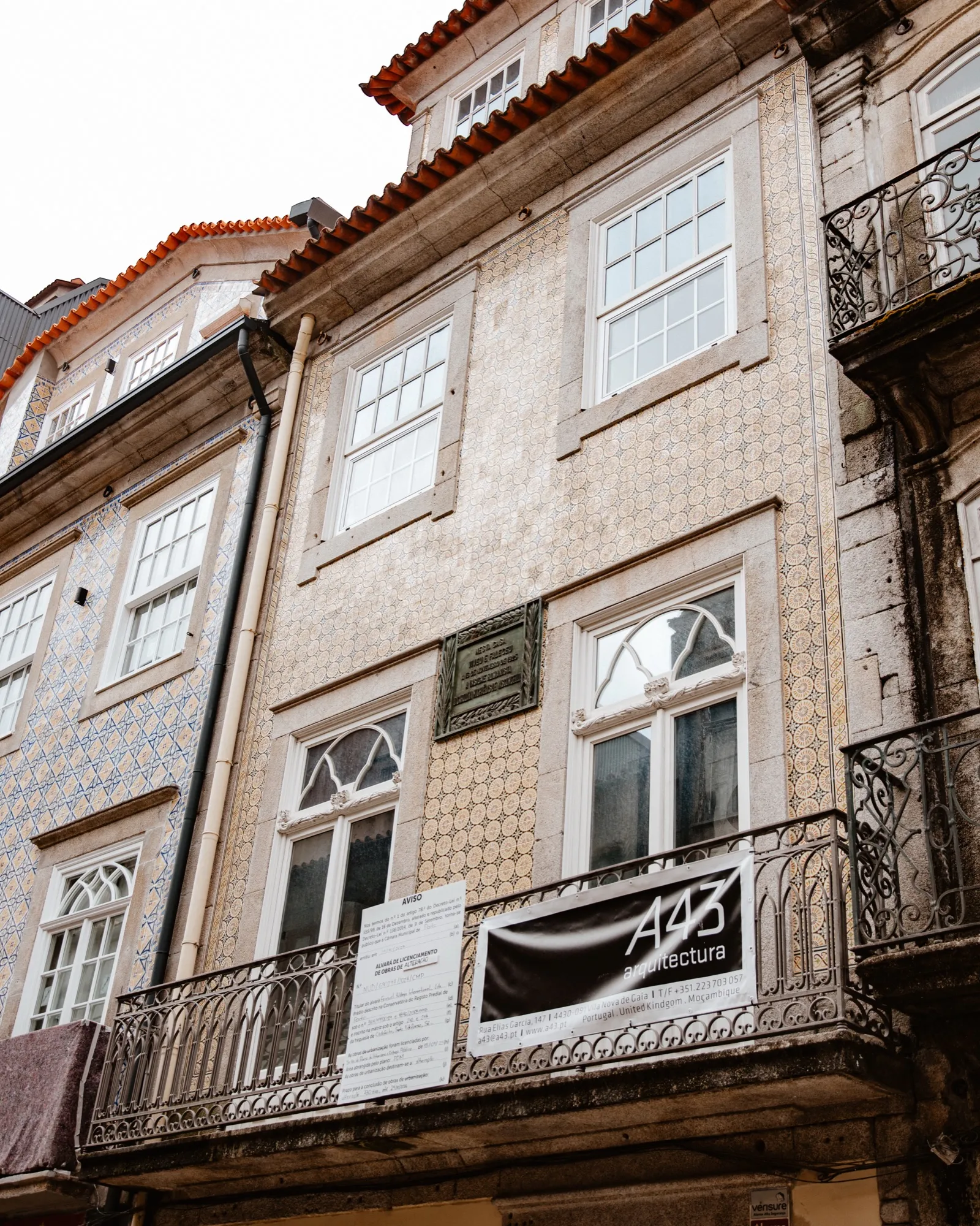 Fachada com azulejos e uma placa comemorativa, numa rua do Porto.