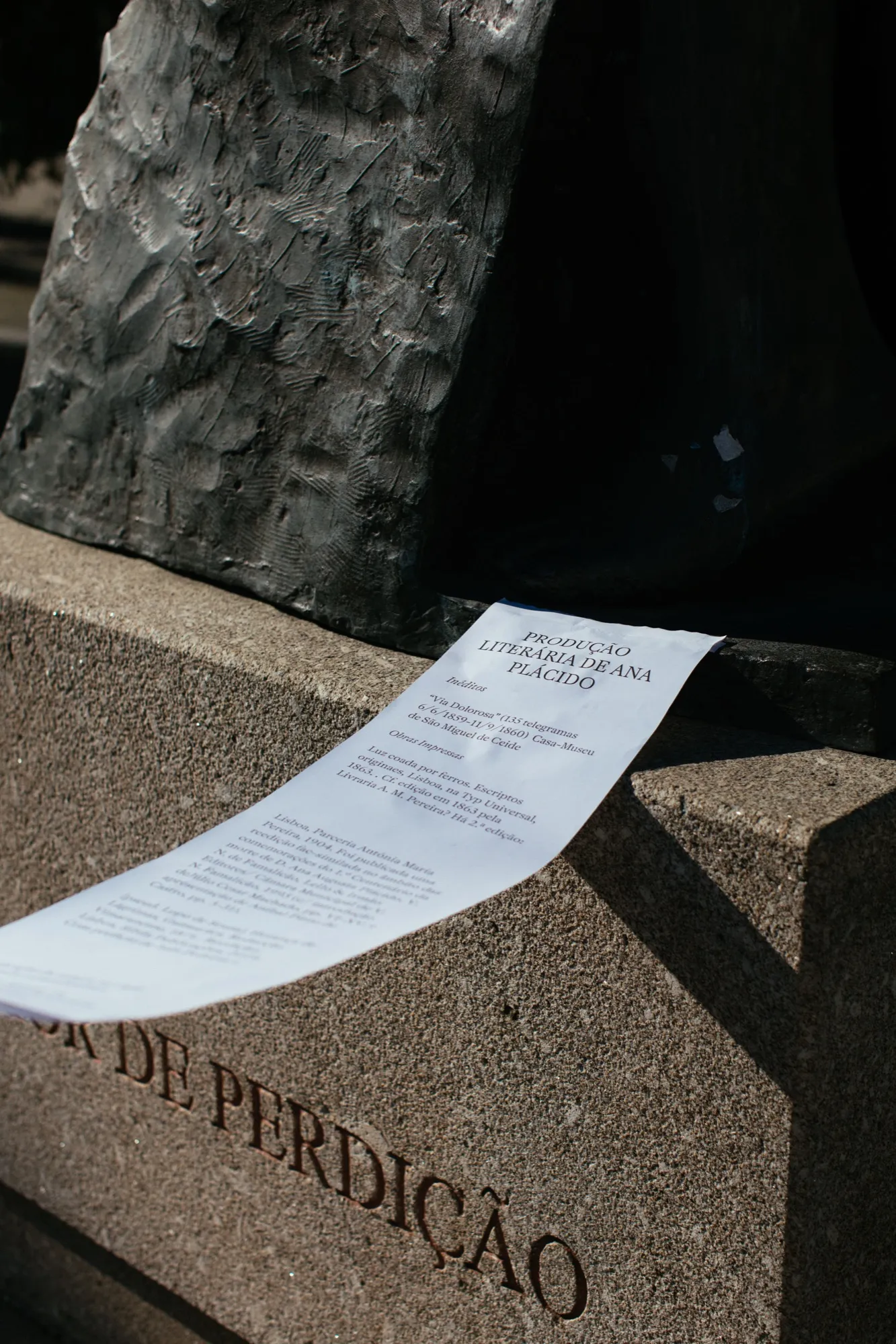 Um poema em papel sobre o pedestal da estátua “Amor de Perdição”.