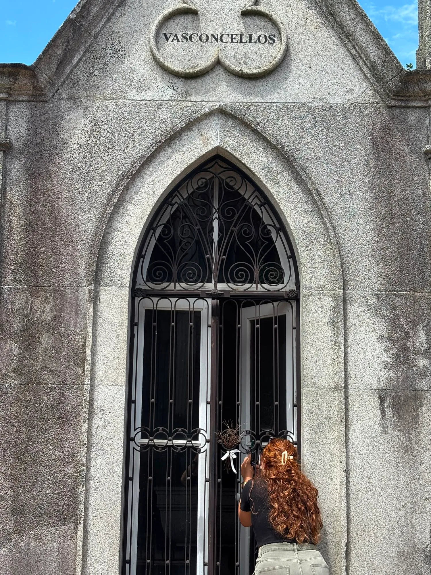 Uma visitante junto ao jazigo da família Vasconcellos, a fotografar a porta em arco gótico.