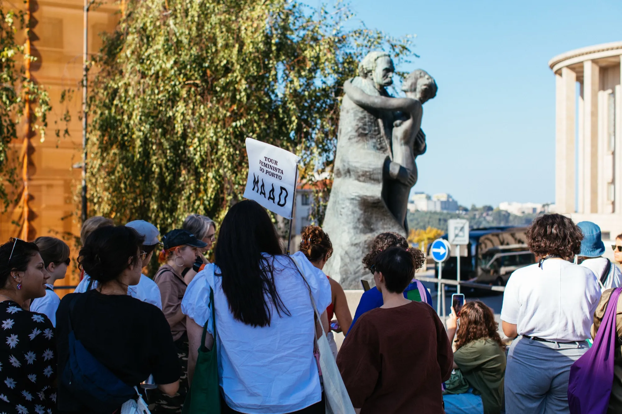 O grupo, com um cartaz do Maad, diante da estátua “Amor de Perdição”.